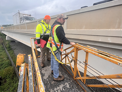 Two engineers inspect a bridge from a reach-all.