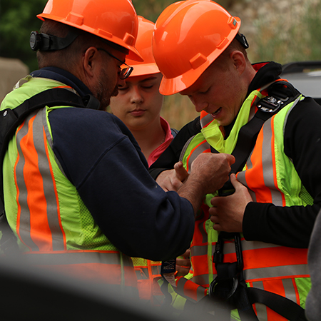 A staff member helps a intern secure their harness.