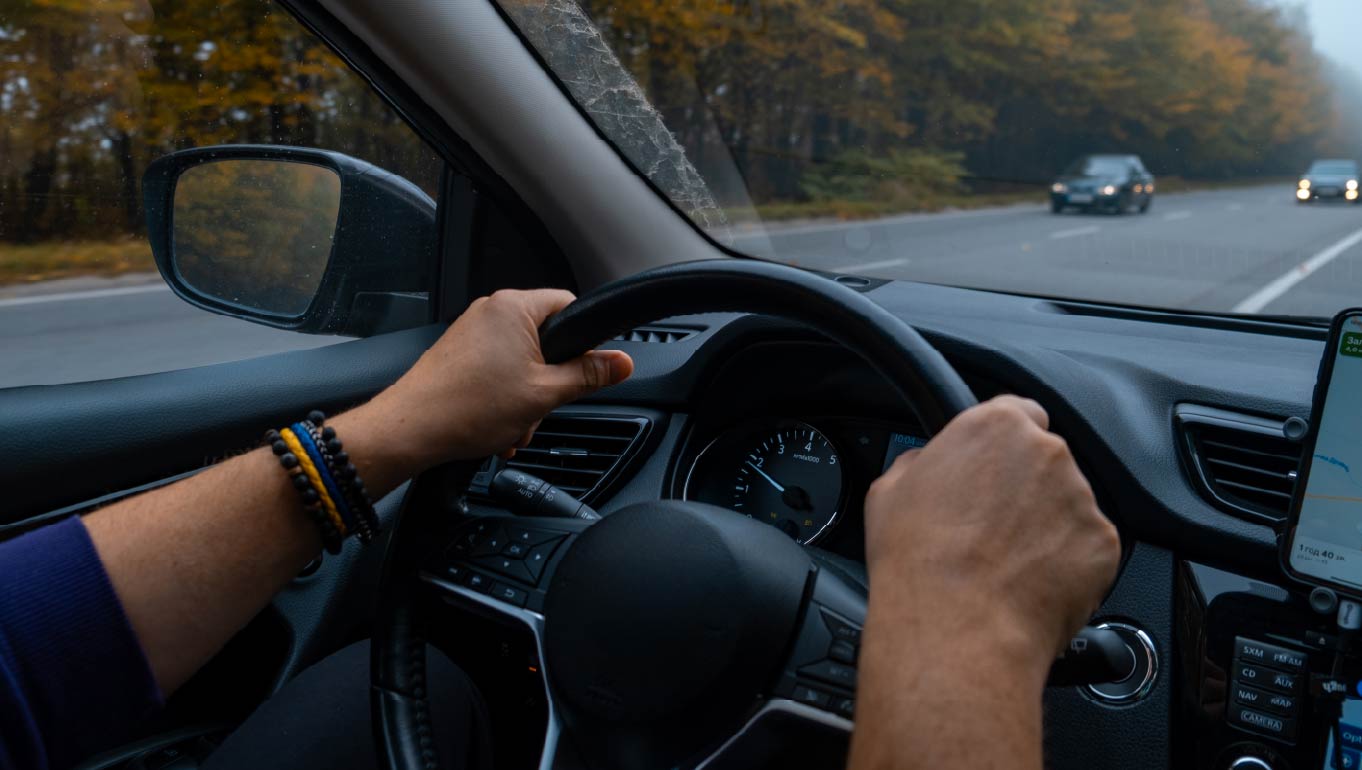 Person driving by the road at foggy autumn highway
