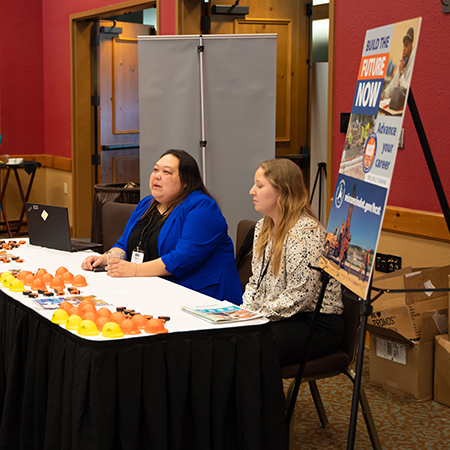 Two women seated behind an exhibit booth