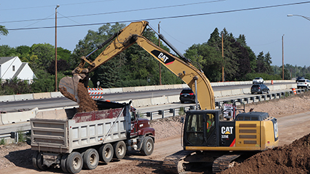 A backhoe moving materials into a dump truck.