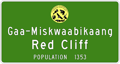 Green road sign that says Gaa-Miskwaabikaang, Red Cliff, and population 1353.