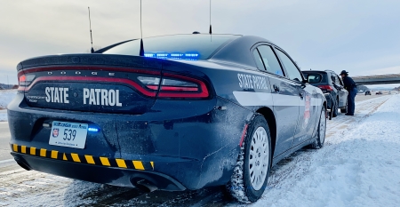 A state patrol car is pulled over on the side of the road behind another driver, who has been pulled over for speeding.