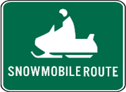A green sign with white letters and a snowmobile. The sign says "Snowmobile Route."