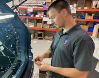 Technician working on wiring in the trunk of a patrol vehicle.