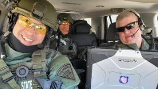 Three Wisconsin State Patrol SWAT officers in SWAT gear inside a vehicle