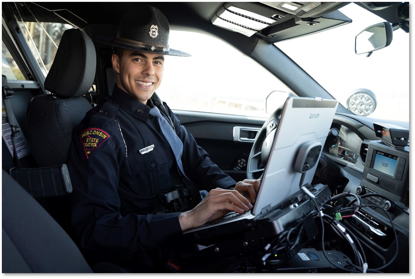 WSP trooper sitting in cruiser at computer, looking out the passenger window