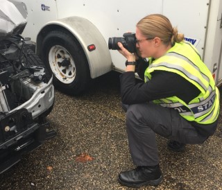 A WSP officer taking an upclose photo in a vheicle yard