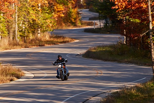 A motorcyclist rides along an empty WIS 42 in fall color