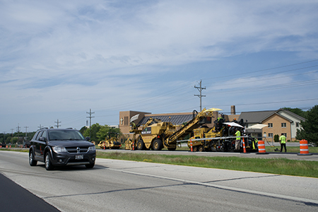 Asphalt paving taking place on a highway in front of a business