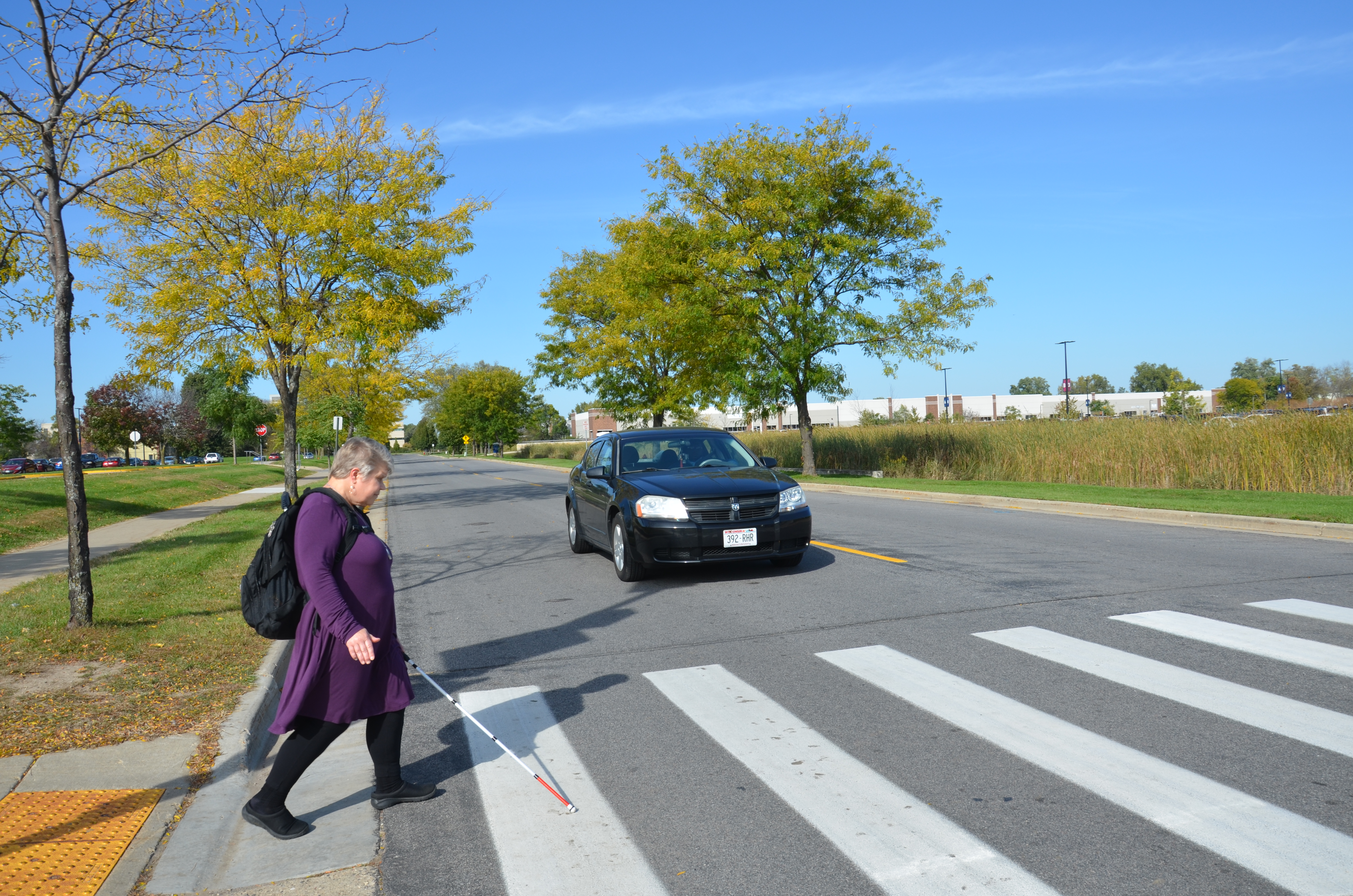 Person showing woman with a visual impairment safely crossing at a crosswalk